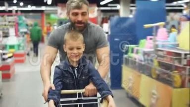 可爱的父亲和他可爱的小儿子在超市里玩得很开心，他带着小购物车跑着